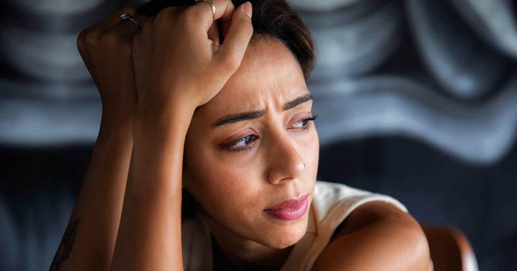 Uma mulher com a mão na cabeça com sintomas da depressão feminina
