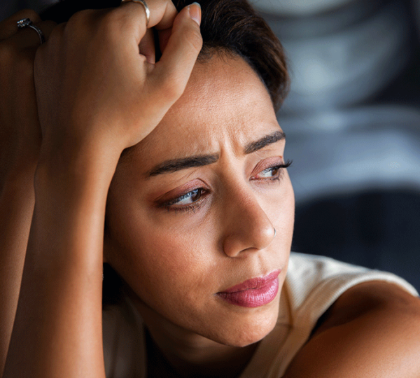 Uma mulher com a mão na cabeça com sintomas da depressão feminina