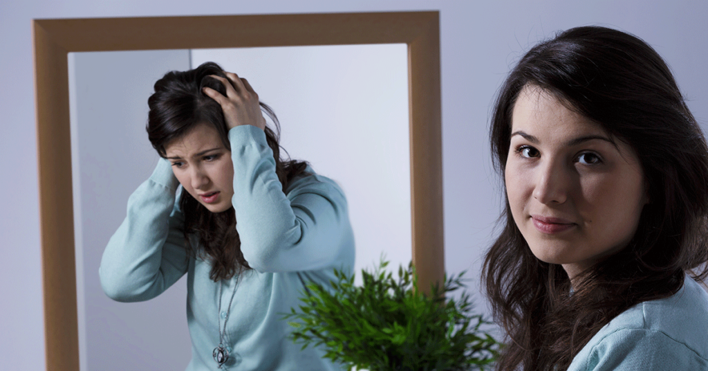 Uma jovem na frente do espelho refletindo emoções diferentes do transtorno bipolar.