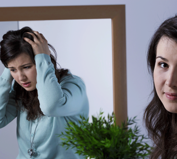Uma jovem na frente do espelho refletindo emoções diferentes do transtorno bipolar.